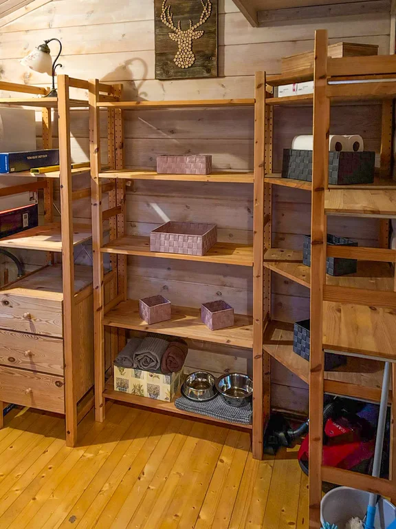 Foto einer Abstellkammer mit Holzregal für Reisegepäck aber auch Haushaltsgeräte und Reinigungsequipment